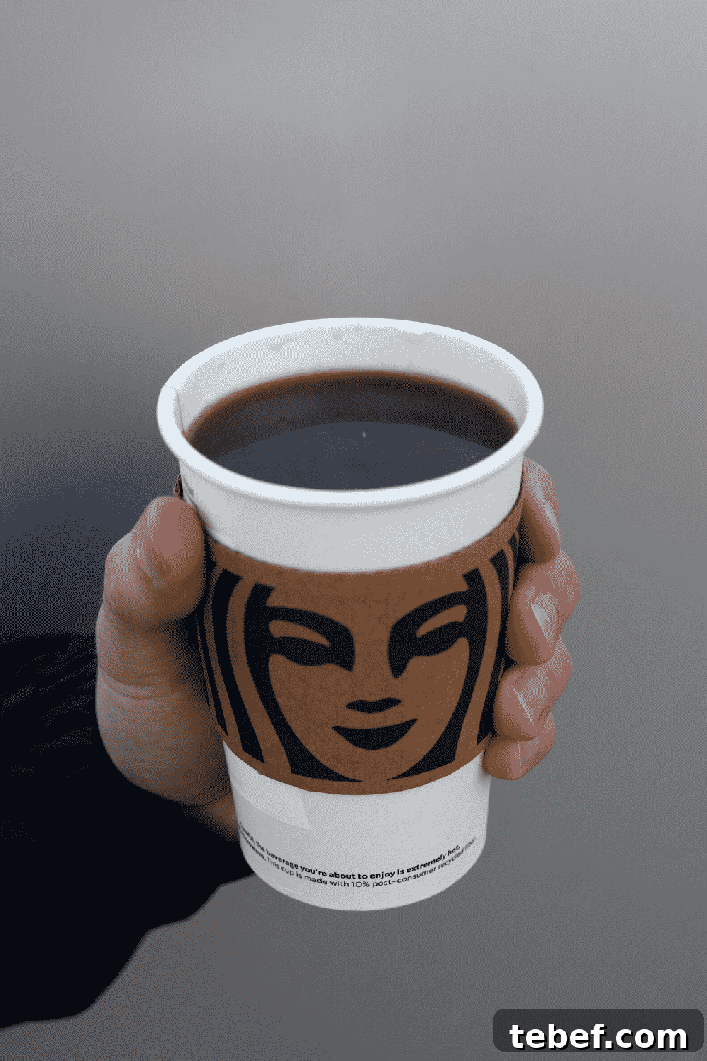 A hand holding a cup of Starbucks vegan caffe Americano