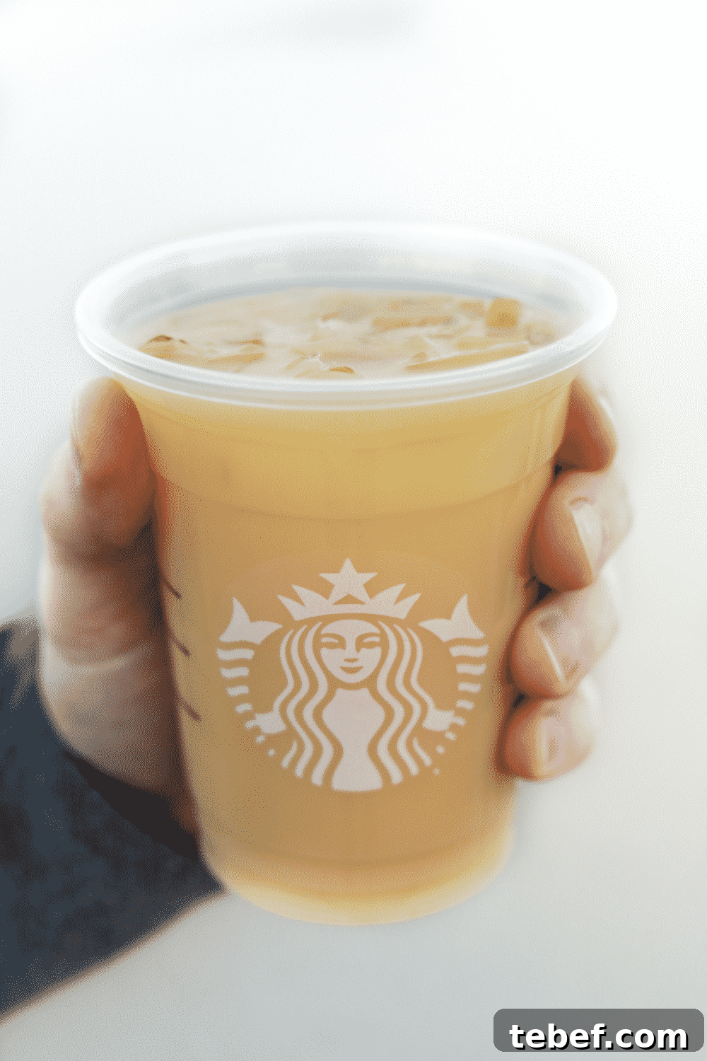 A hand holding a cup of Starbucks vegan iced royal English breakfast tea latte