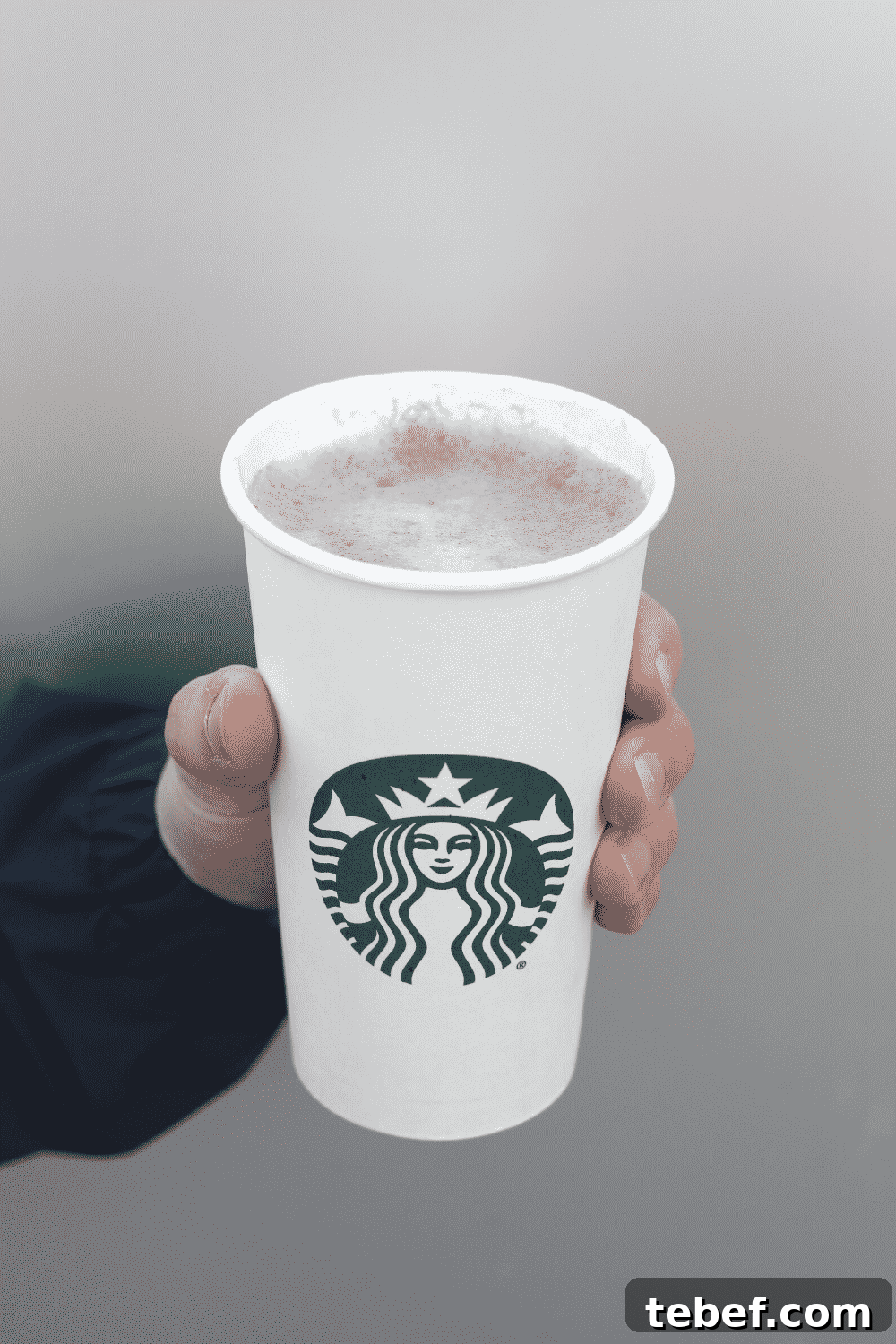 A hand holding a cup of Starbucks vegan hot chocolate.