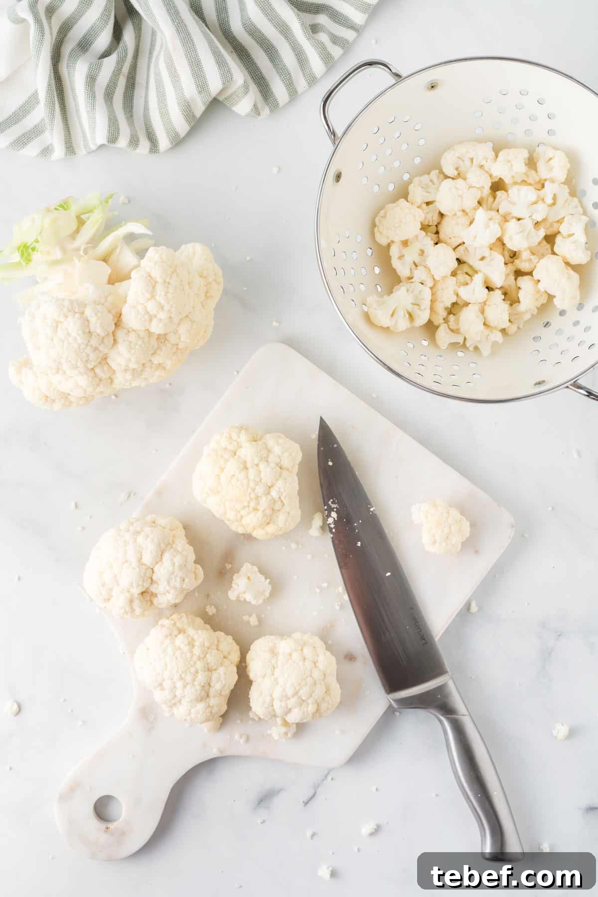 cutting board with cauliflower being cut with a knife