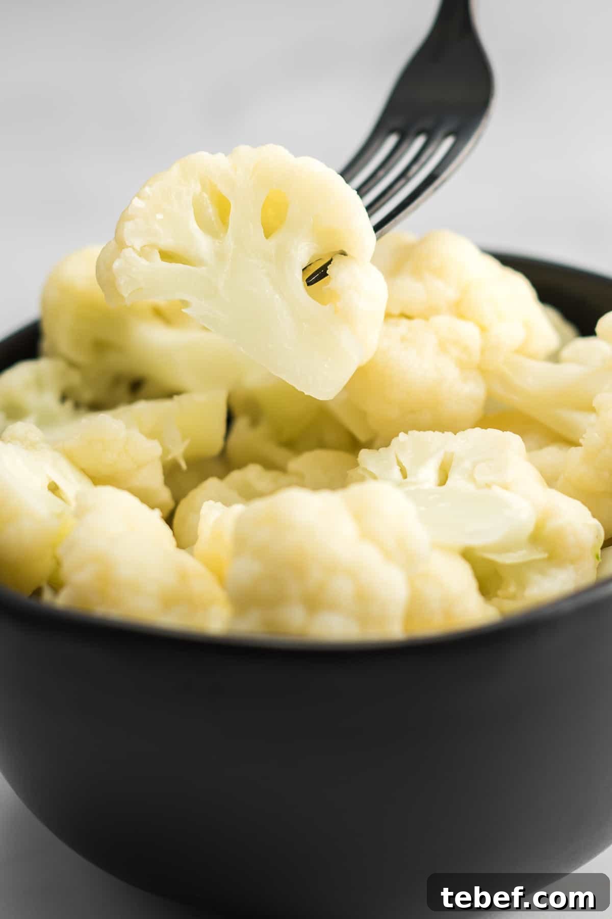 fork taking a floret of cauliflower from a bowl