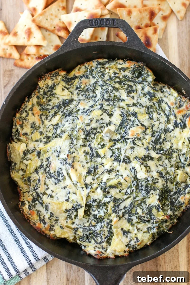 Ever wonder how to make spinach artichoke dip perfectly creamy? Try this perfect baked, hot spinach artichoke dip. hot spinach artichoke dip in a skillet on a table