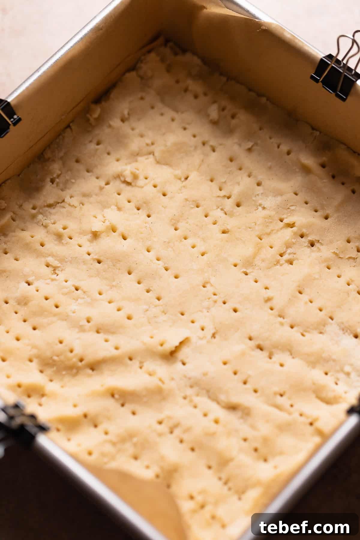 Zesty Lemon Bars with Buttery Shortbread Crust 4 Shortbread dough pressed into a square pan pricked with a fork before baking.