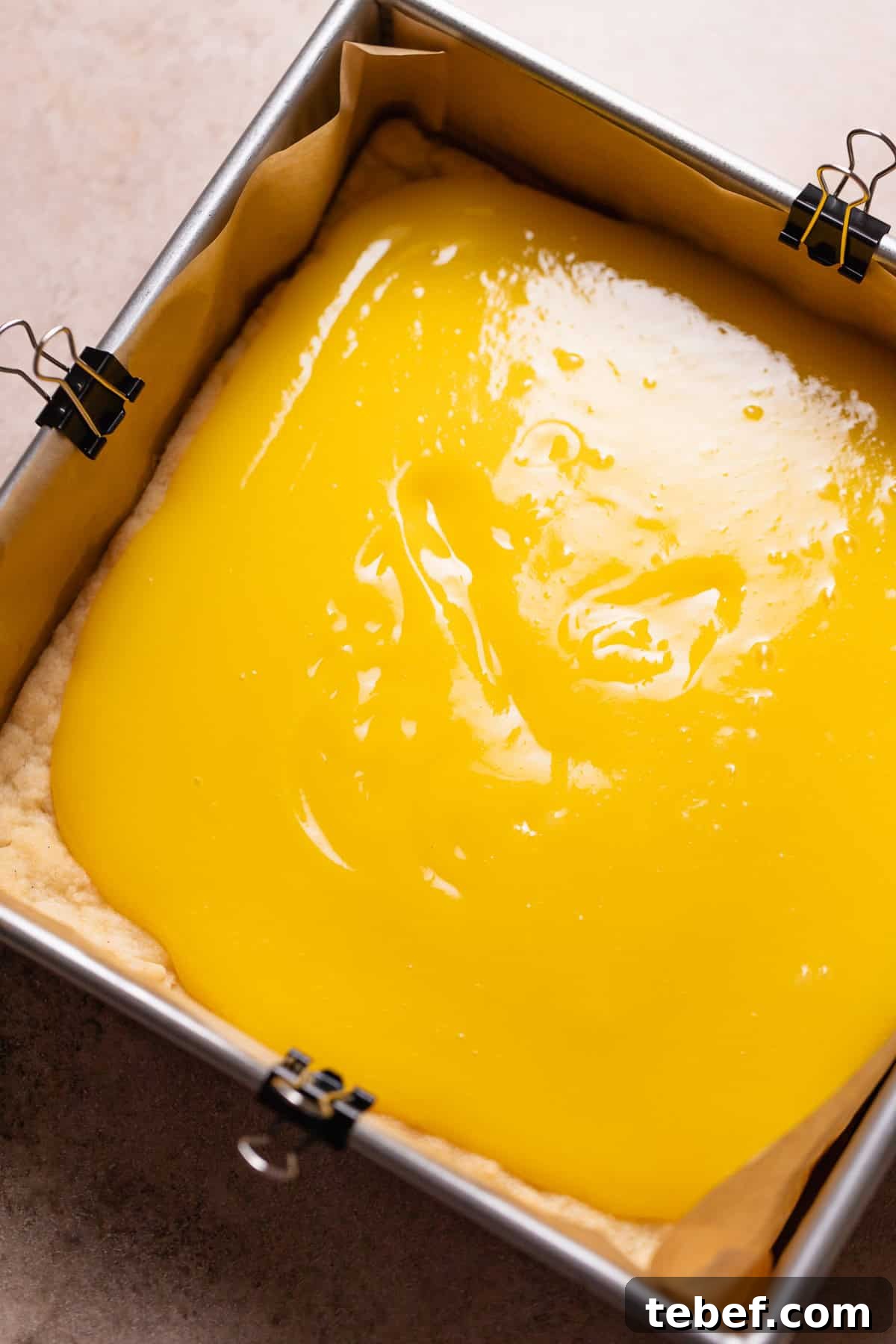 Zesty Lemon Bars with Buttery Shortbread Crust 7 Lemon curd being spread over the top of the baked shortbread crust.