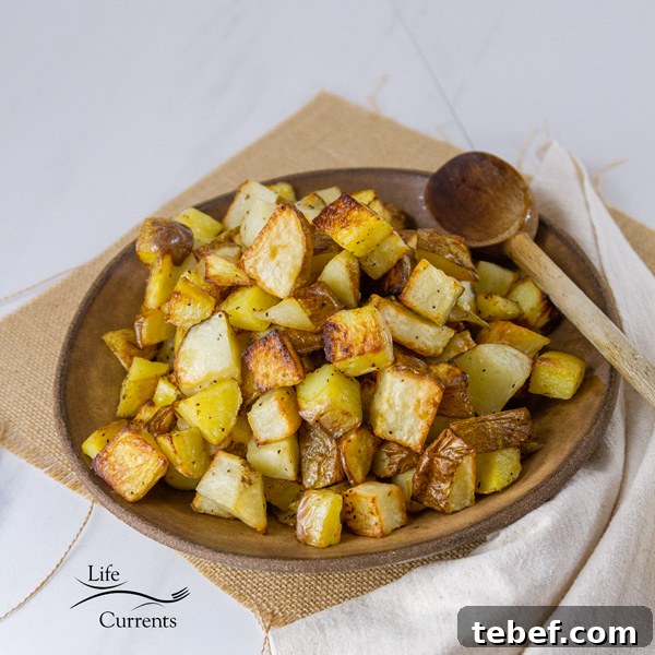 Sheet Pan Roasted Potatoes are an easy, delicious side dish for any meal. This super easy method produces perfectly cooked potatoes that are crispy outside and tender and creamy inside. Square crop of Potatoes in a brown bowl with a spoon
