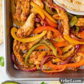 Overhead view of sheet pan fajitas with chicken, peppers, and onions.