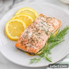 Salmon on a white plate with lemon slices.