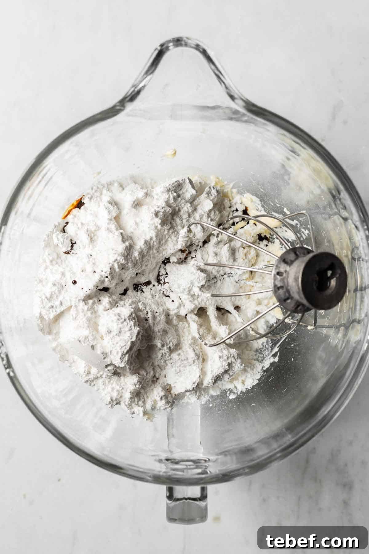 Butter, powdered sugar, espresso powder, vanilla and salt in a glass mixing bowl for frosting.