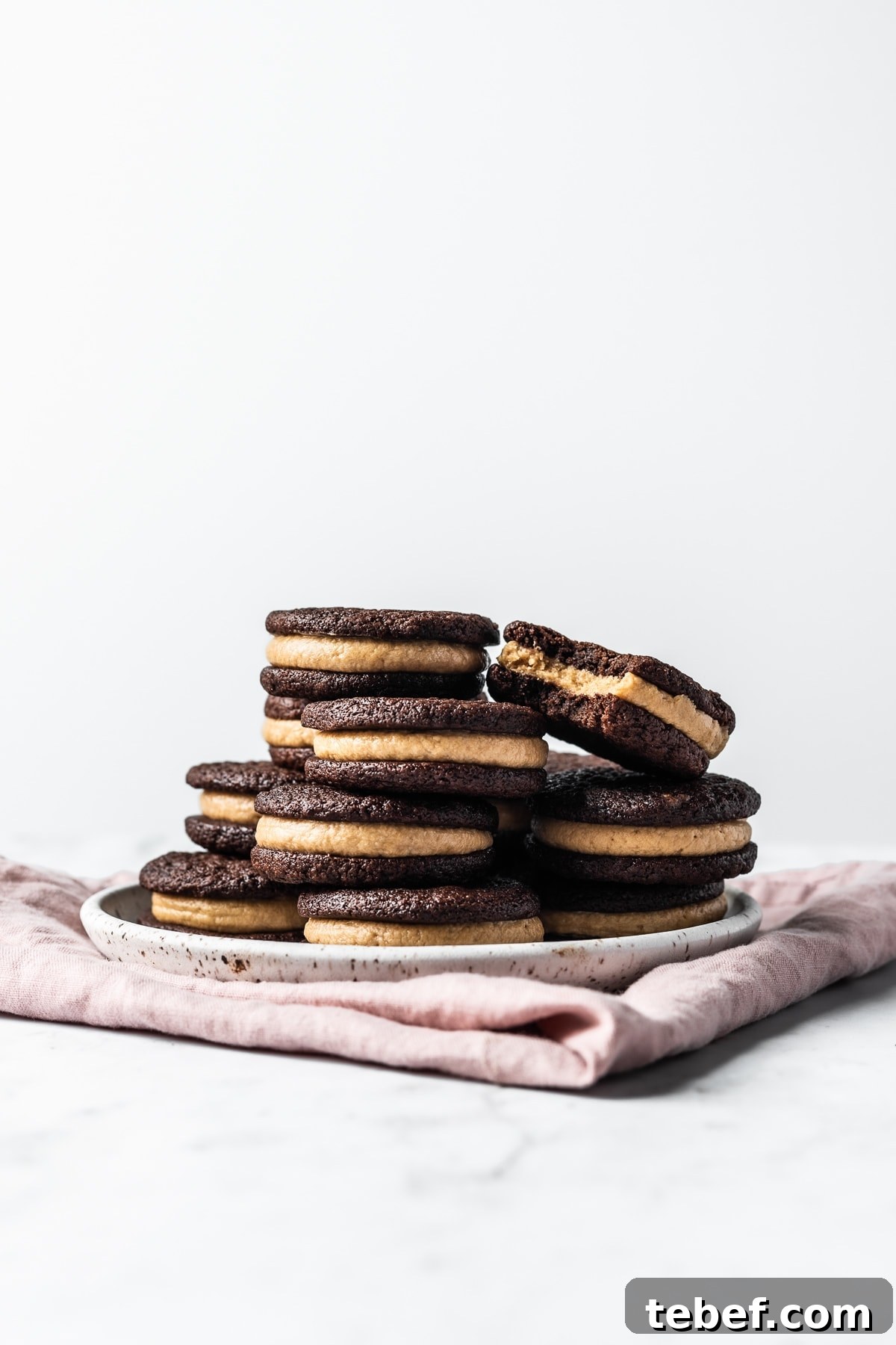 A stack of sandwich cookies on a ceramic plate. 