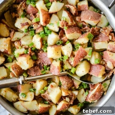 Ultra-Creamy Mashed Potatoes Recipe for Perfect Texture 12 german potato salad with diced red potatoes, green onions, and bacon in a stainless steel skillet on a marble surface