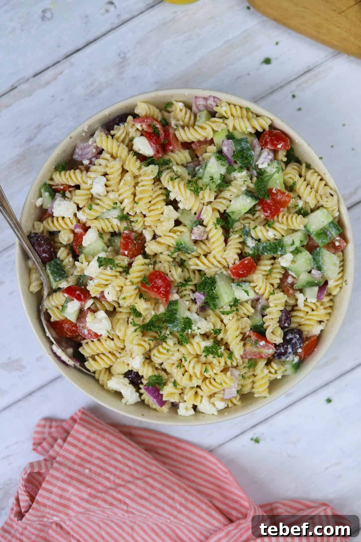 Classic Greek Pasta Salad Recipe for Mediterranean Flavor 6 A bowl of Greek pasta salad on a white wooden backdrop.