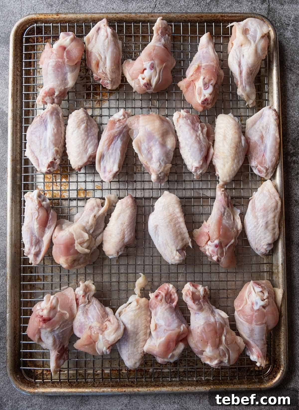 How to Cut Whole Chicken Wings Into Flats and Drumettes for Perfect Portions 12 Two dozen raw chicken wings on a baking sheet.