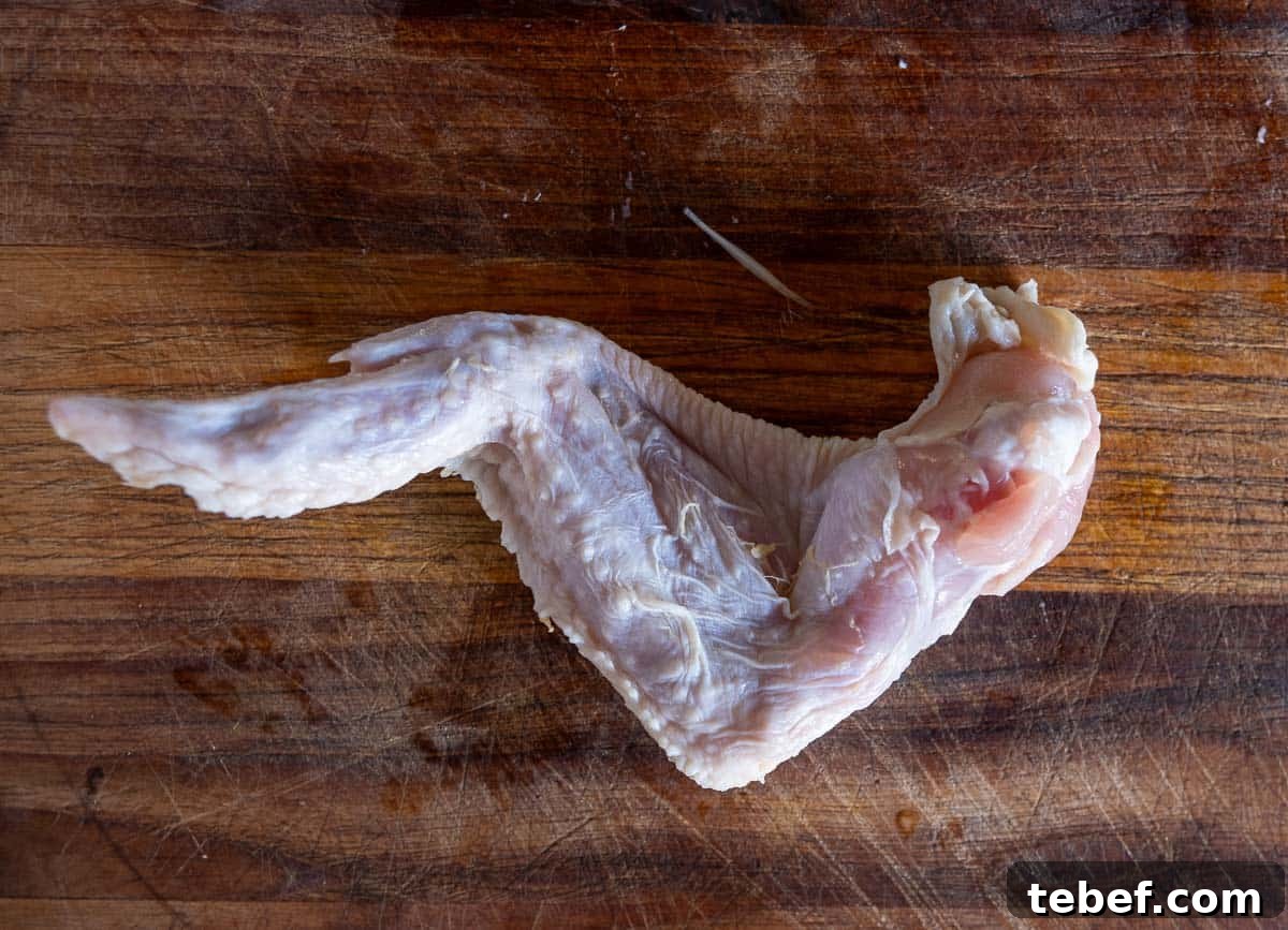 How to Cut Whole Chicken Wings Into Flats and Drumettes for Perfect Portions 4 The back side of a whole chicken wing, not yet separated into the drum, flat, and winglet.