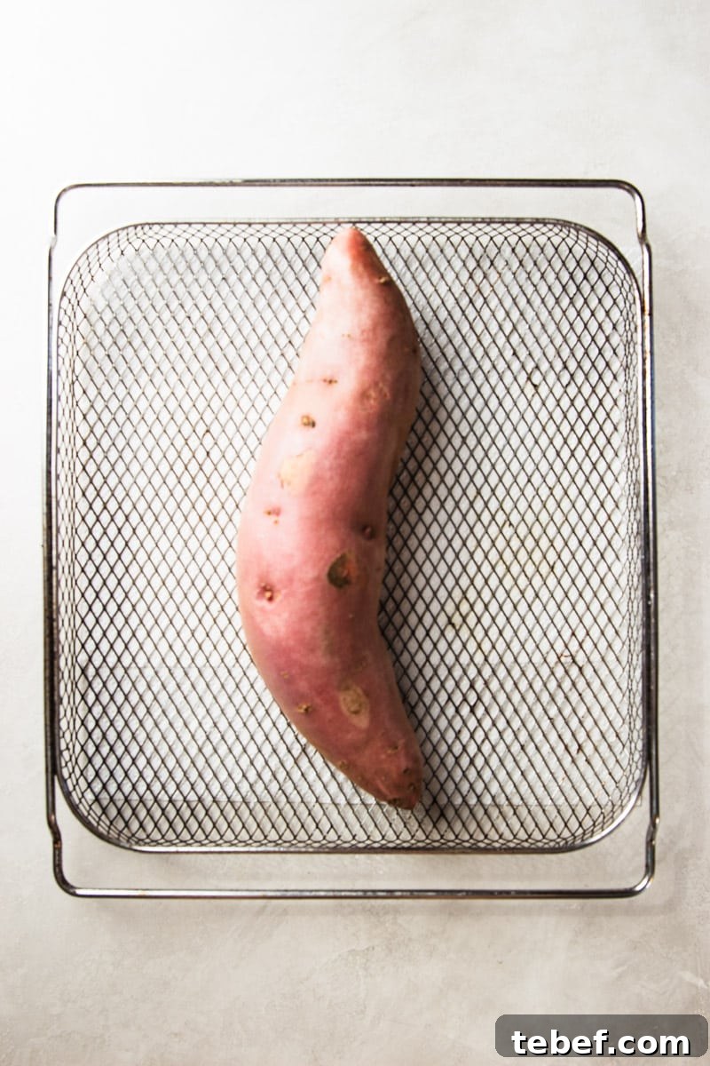 Maple Pecan Sweet Potatoes in the Air Fryer: Crispy & Caramelized 3 Unpeeled sweet potato in an air fryer basket.