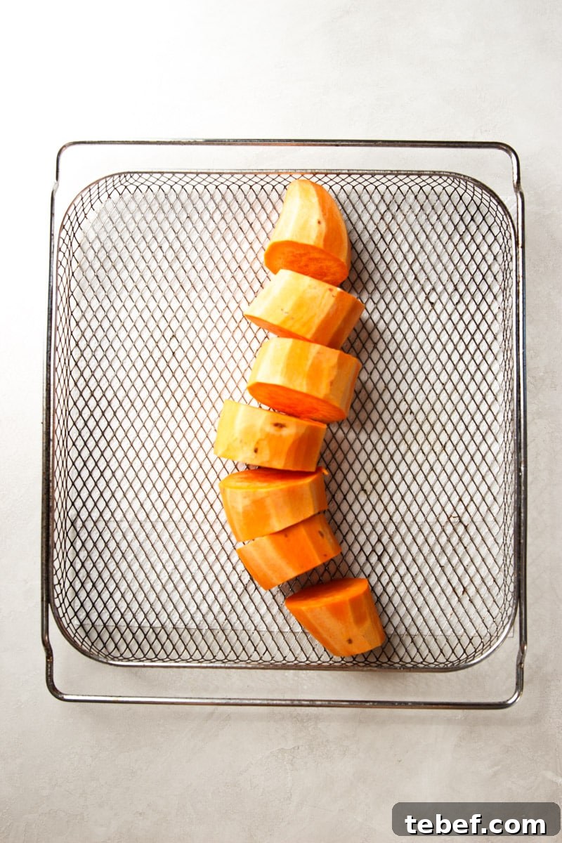 Maple Pecan Sweet Potatoes in the Air Fryer: Crispy & Caramelized 4 Peeled and chopped sweet potato in an air fryer basket.
