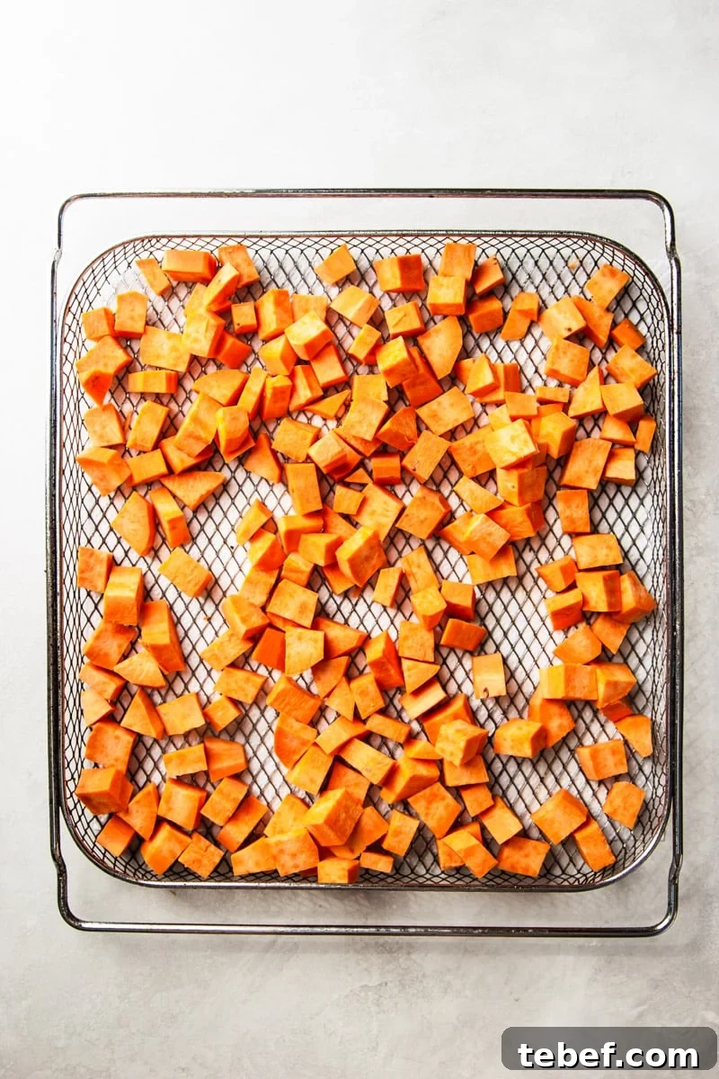 Maple Pecan Sweet Potatoes in the Air Fryer: Crispy & Caramelized 5 Peeled and cubed sweet potato in an air fryer basket.