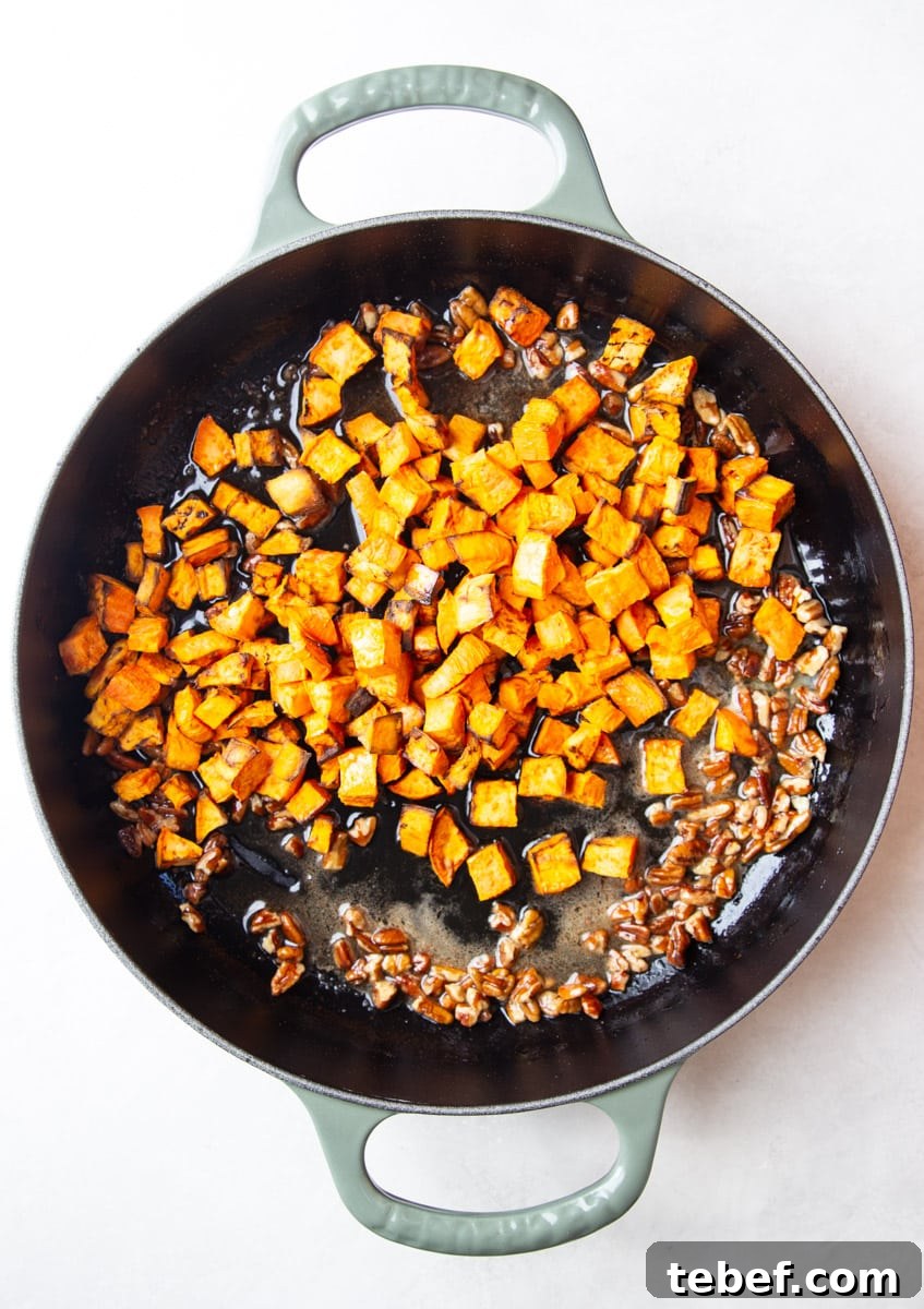 Maple Pecan Sweet Potatoes in the Air Fryer: Crispy & Caramelized 7 Cooked sweet potato in a skillet with pecans and maple butter.