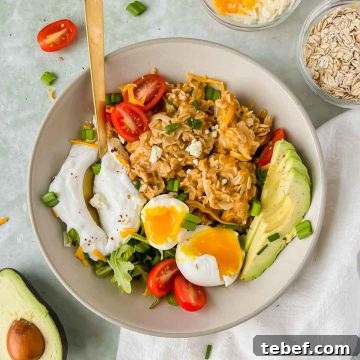 Savory Cheesy Oatmeal Recipe: Comforting Savory Oats in 15 Minutes 11 cheesy oatmeal topped with avocado, egg, yogurt, and herbs with a gold spoon in a ceramic bowl on a gray slate background.