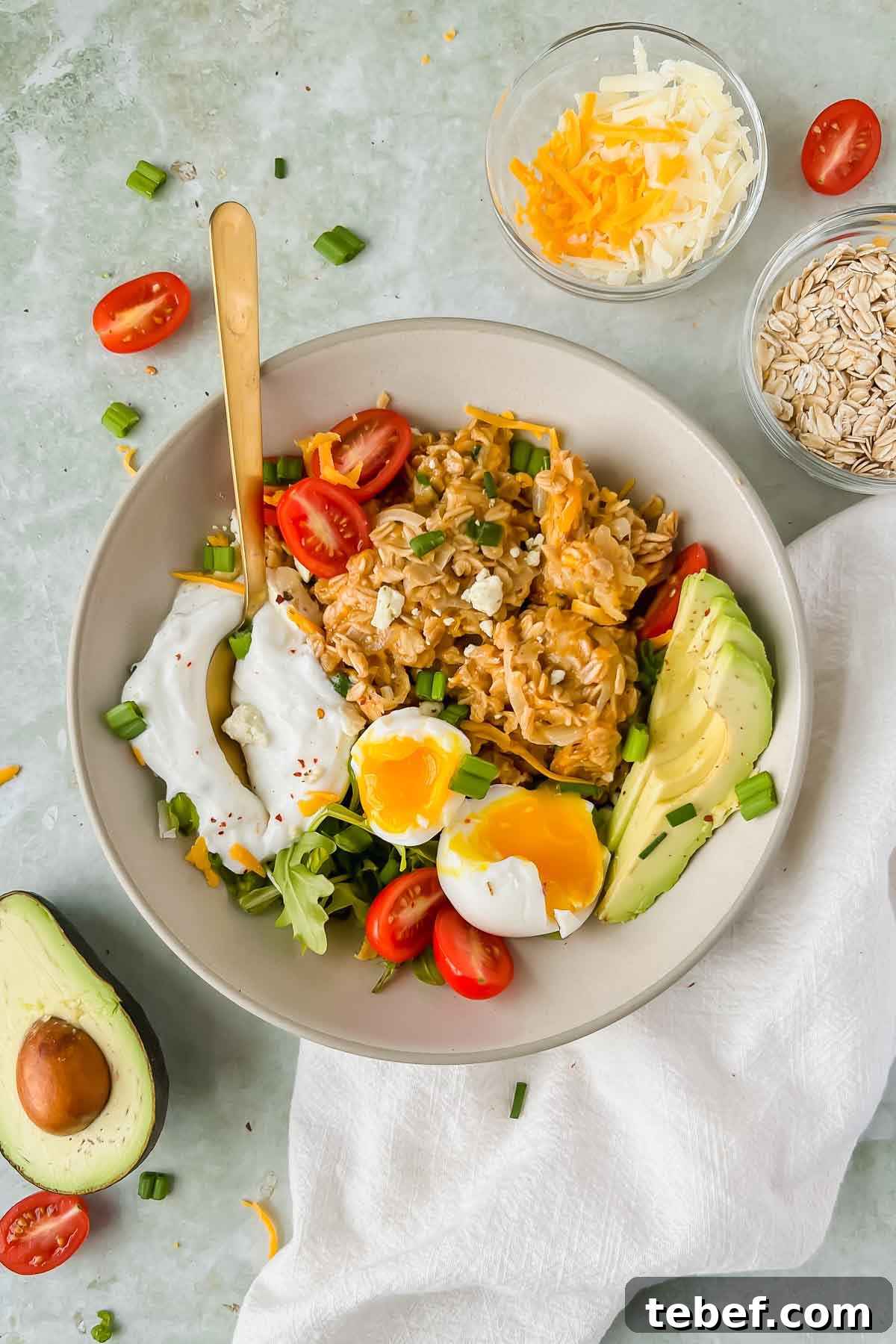 Savory Cheesy Oatmeal Recipe: Comforting Savory Oats in 15 Minutes 10 bowl of cheesy oats topped with a soft boiled egg, avocado slices, greek yogurt and green onion.