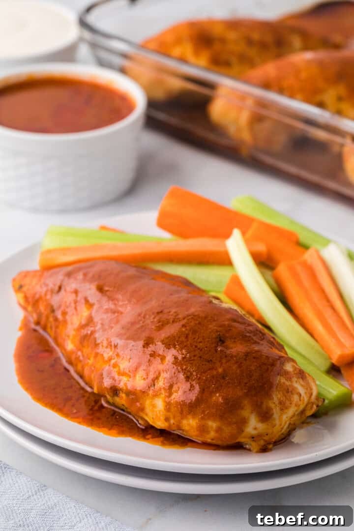 Oven-Baked Buffalo Chicken Thighs with Crispy Skin 9 Buffalo Chicken breast on plate with sliced celery and carrots.