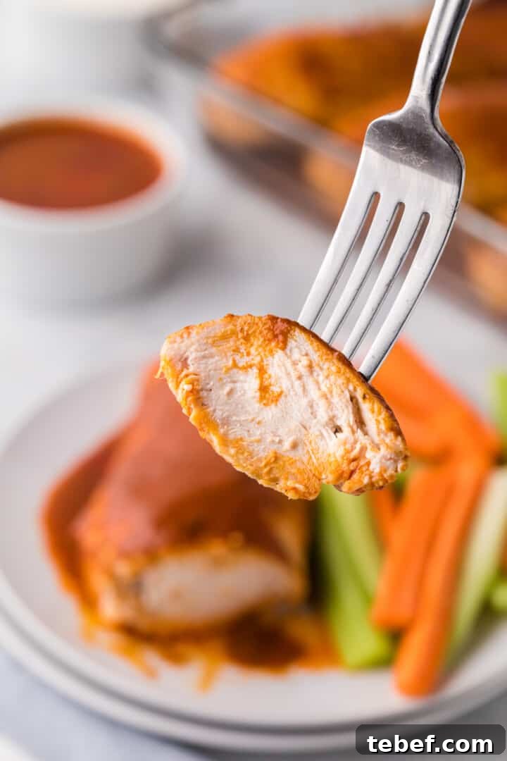 Oven-Baked Buffalo Chicken Thighs with Crispy Skin 10 piece of Buffalo chicken on fork.