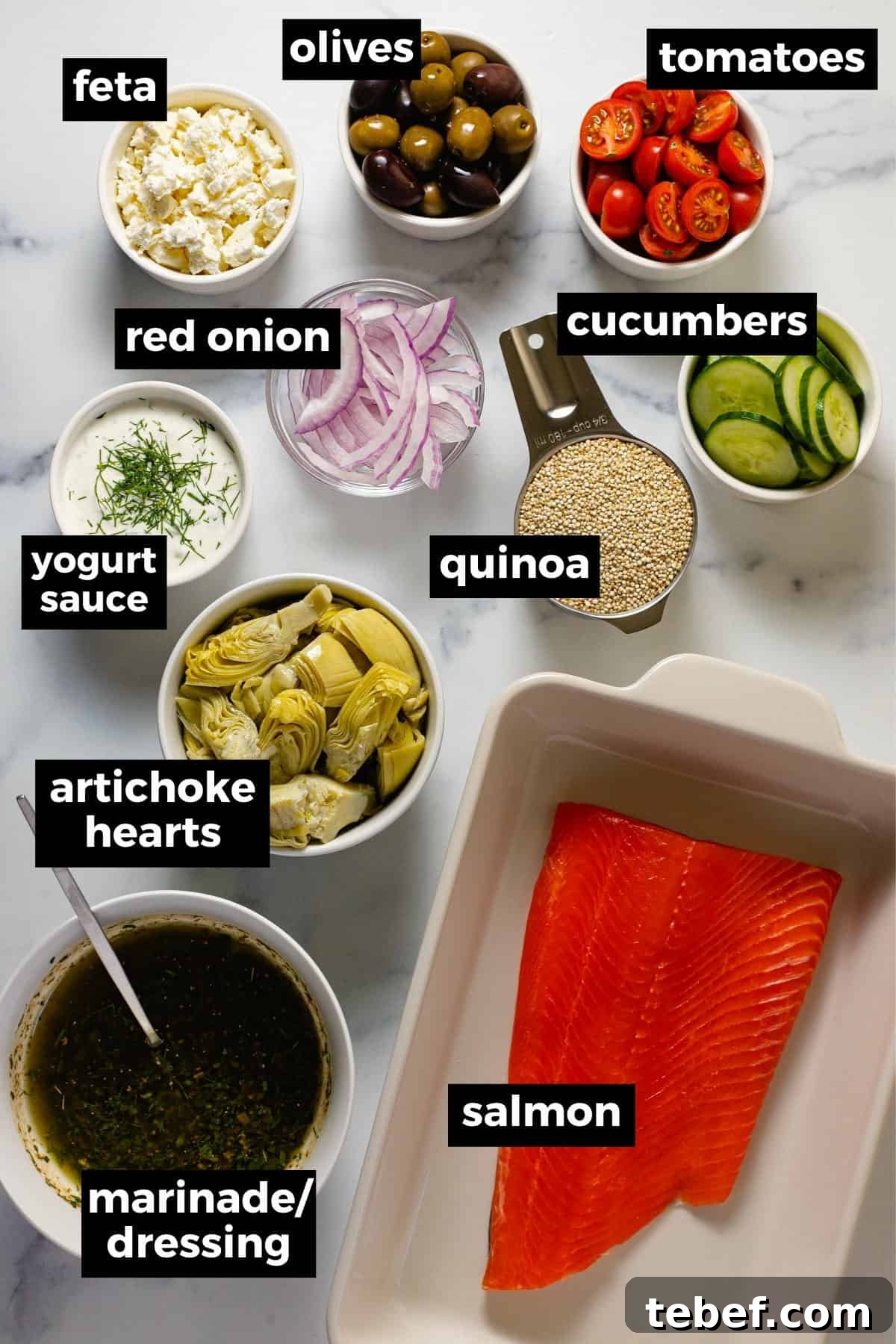 Greek Salmon Bowl Recipe with Lemon-Dill Yogurt Dressing 3 Marble countertop with bowls of ingredients to make Greek salmon bowls