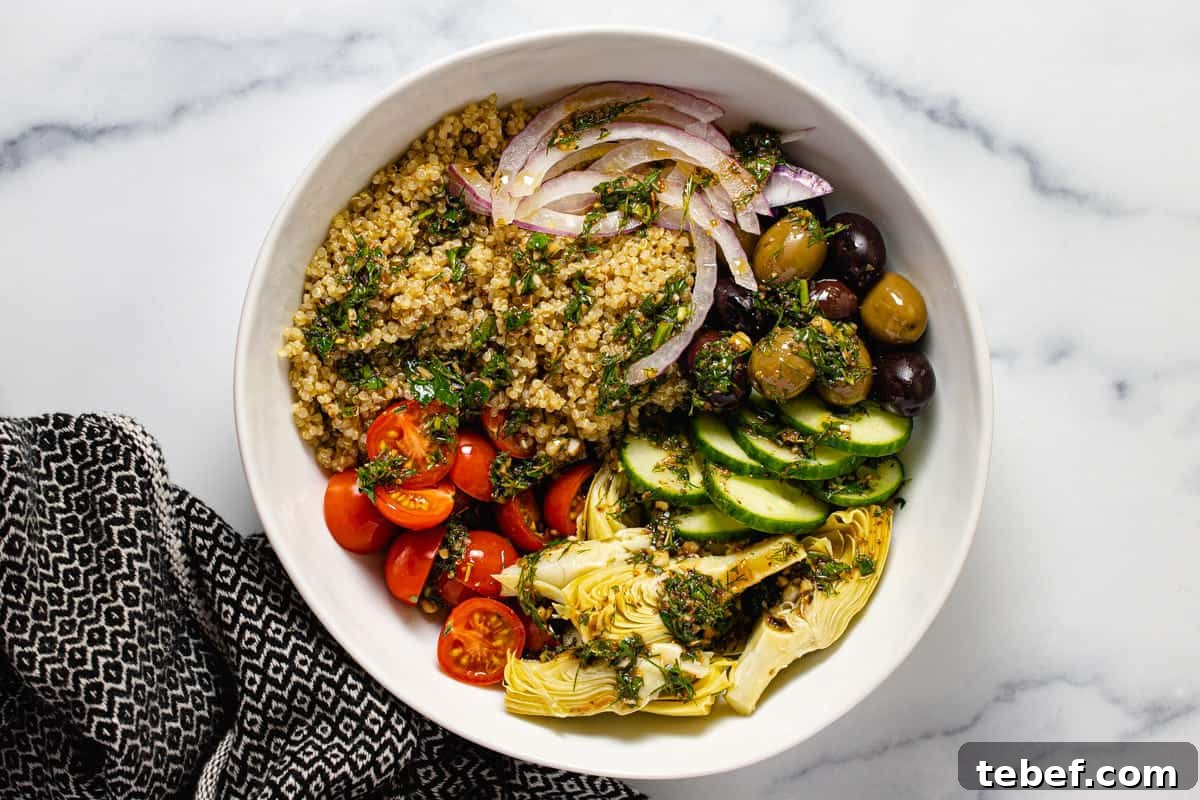 Greek Salmon Bowl Recipe with Lemon-Dill Yogurt Dressing 6 White bowl filled with veggies and quinoa dressed in an herb vinaigrette