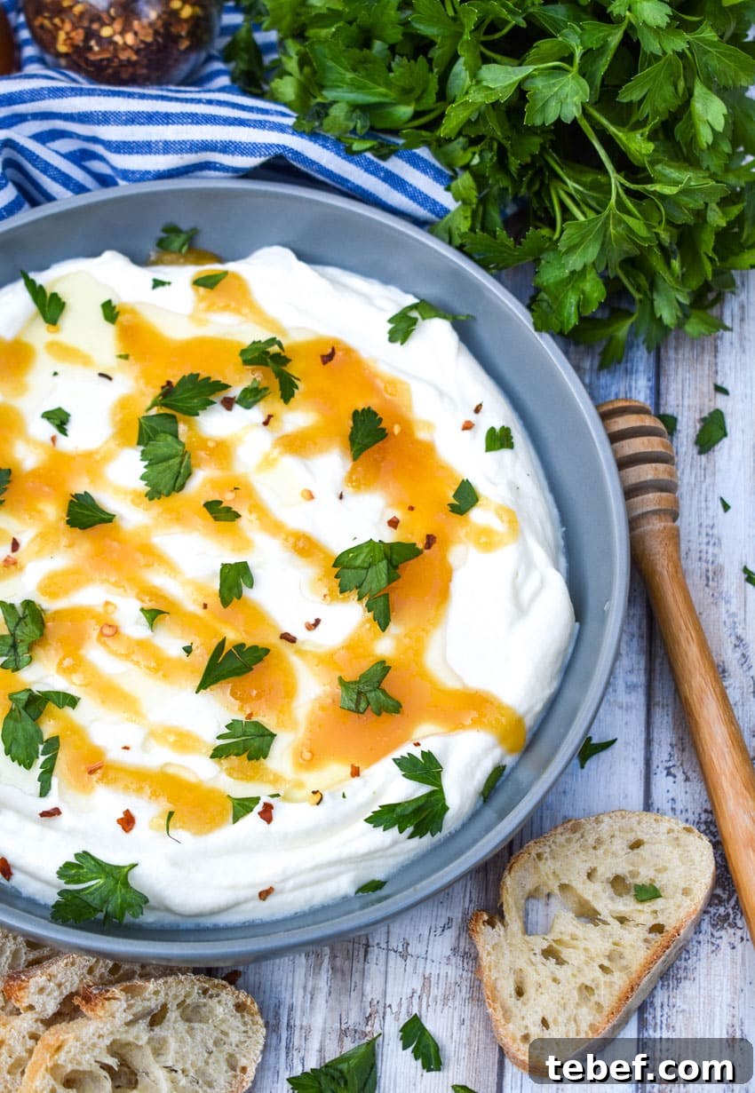 whipped ricotta cheese spread in a shallow gray bowl topped with honey and fresh herbs