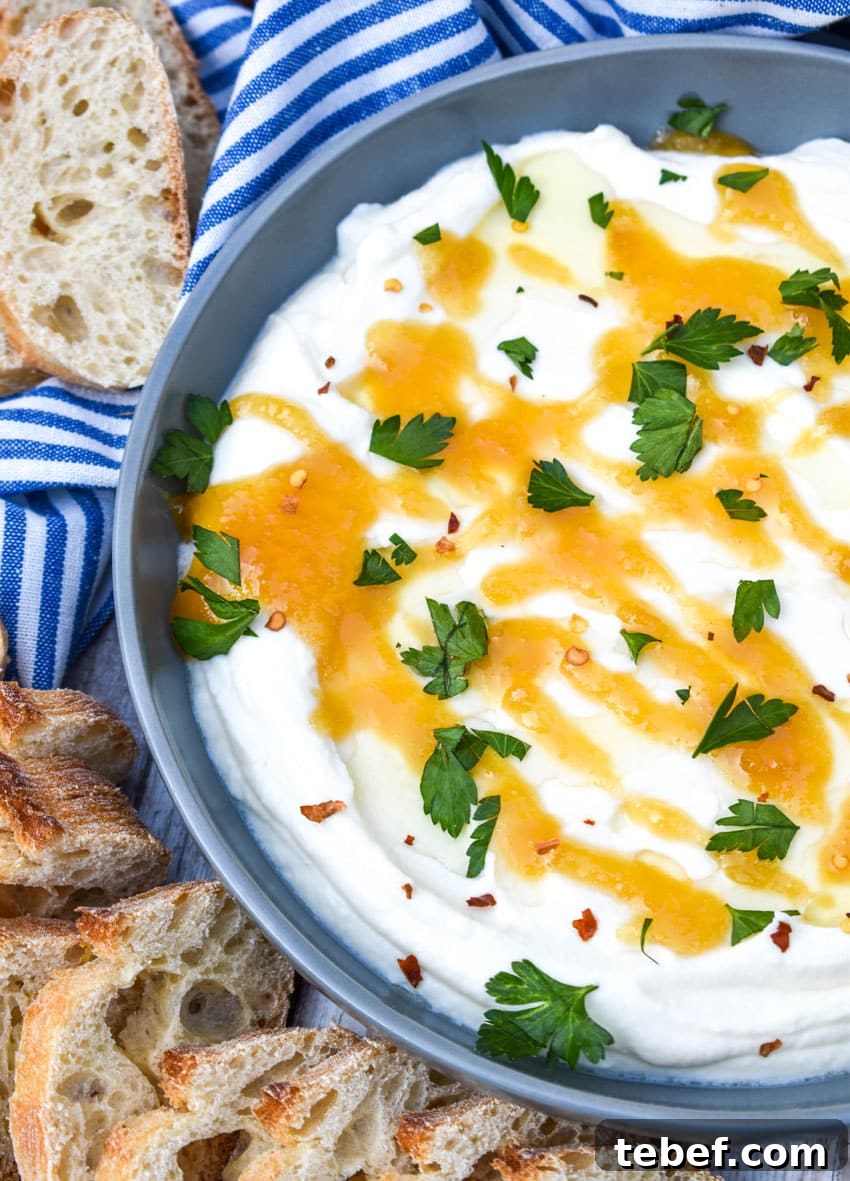 whipped ricotta cheese spread in a shallow gray bowl topped with honey and fresh herbs