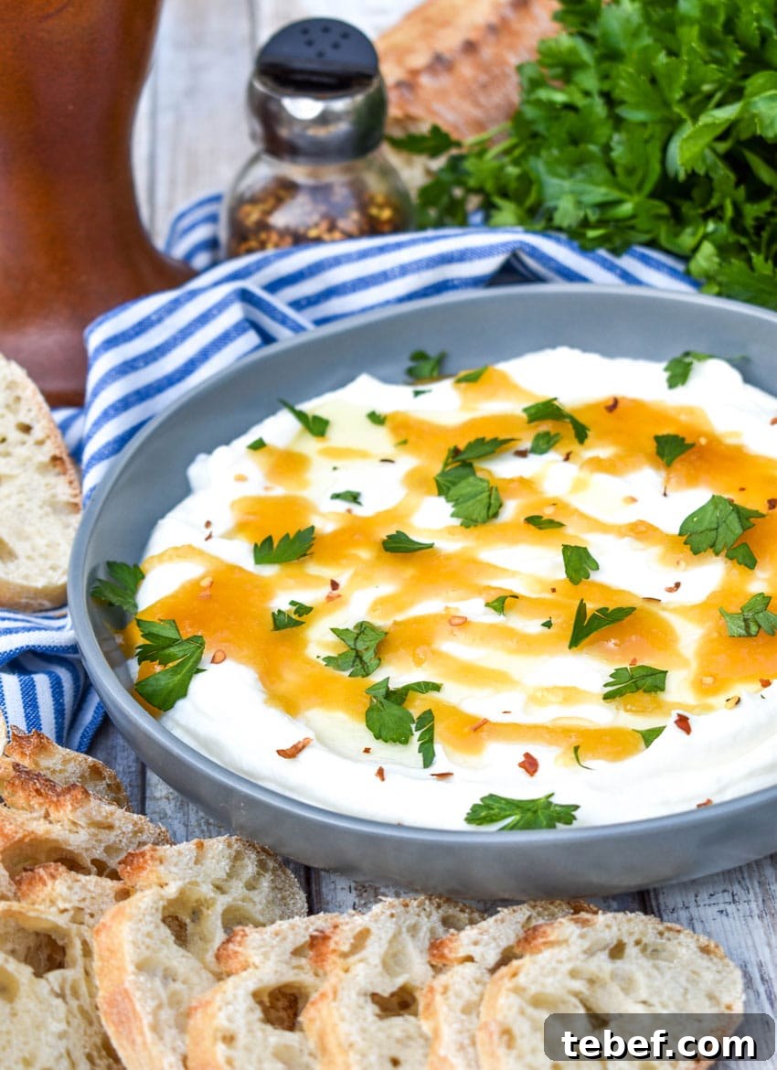 whipped ricotta dip in a shallow gray bowl topped with honey and fresh herbs