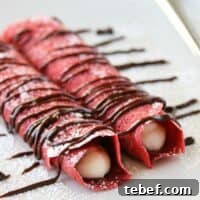 Red Velvet Crepes Recipe: Fluffy, Cream Cheese-Filled Pancake Rolls 2 Two rolled red velvet crepes filled with cream cheese filling and drizzled with chocolate.