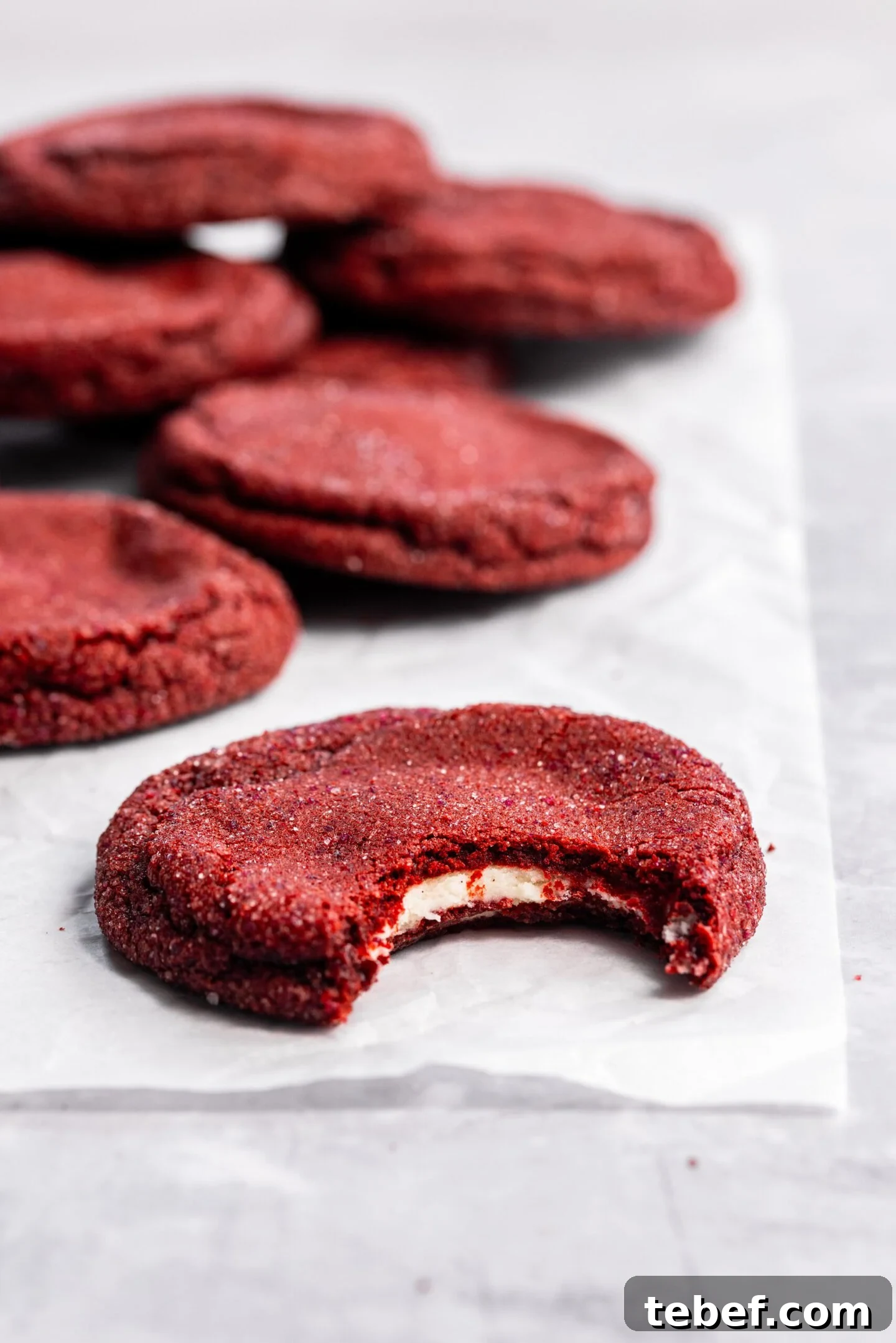Red Velvet Cookies Stuffed with Cream Cheese — 8 Giant Cookies 3 Close up of a bite missing from a red velvet cookie showing off the cream cheese filling hidden inside.