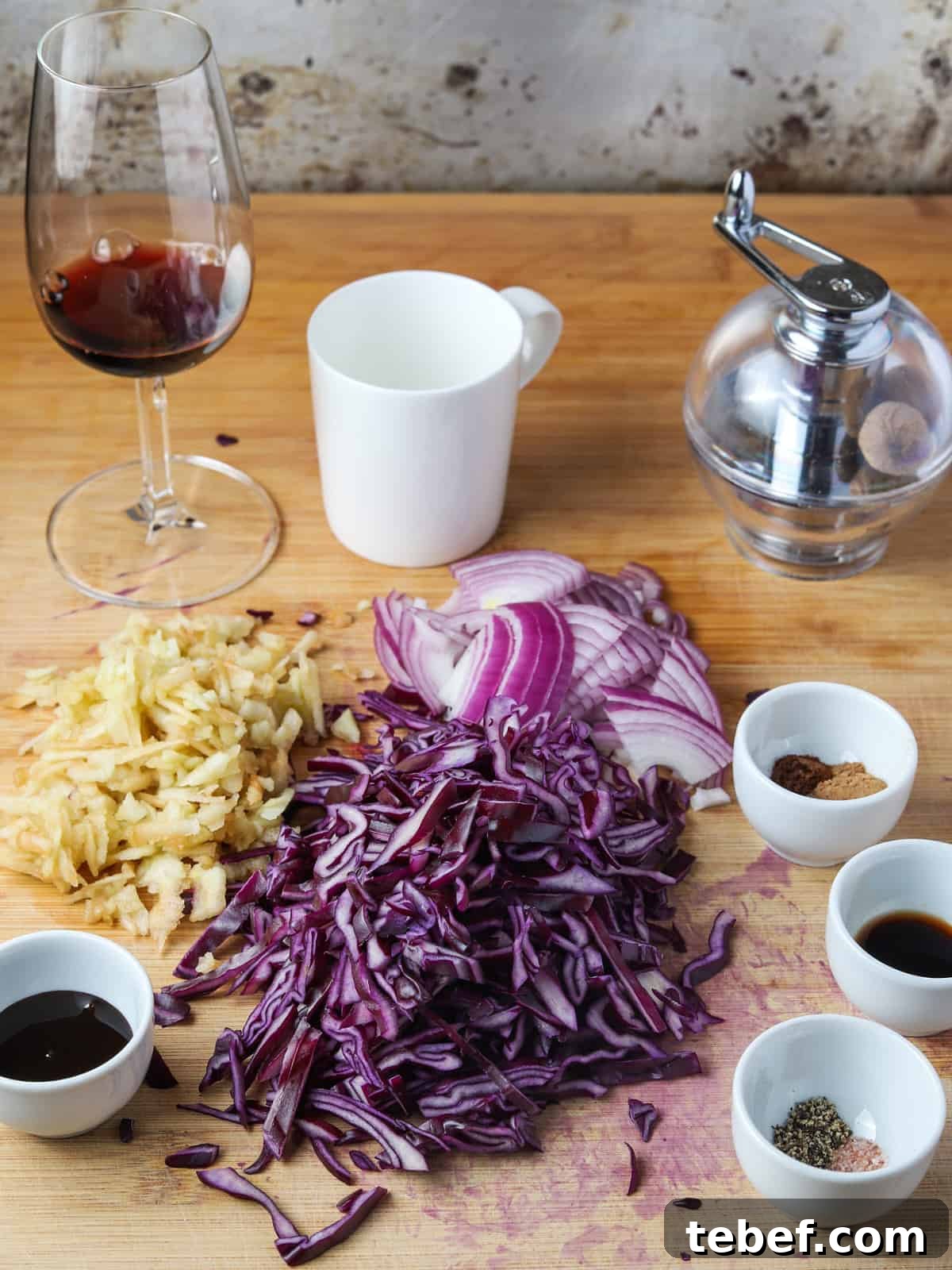 Photo of the ingredients to make braised red cabbage all set out on a chopping board.