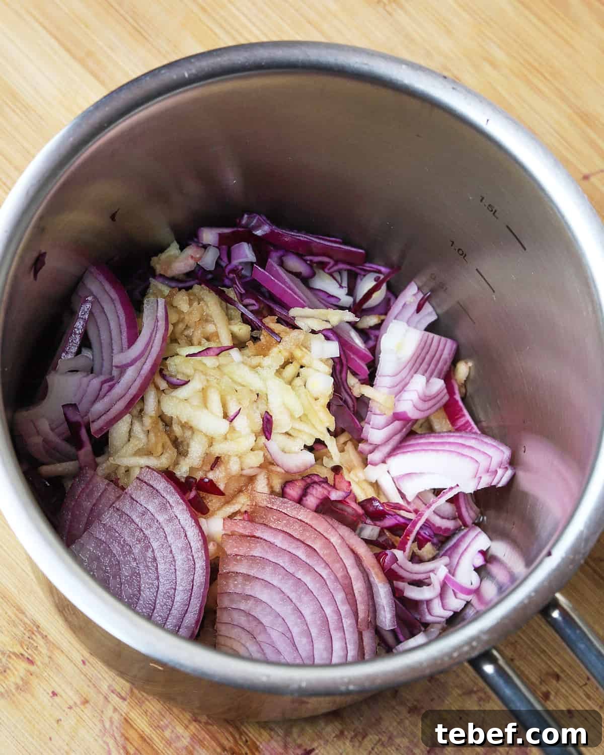 Photo of red cabbage, red onion and apple in the saucepan ready to start cooking.