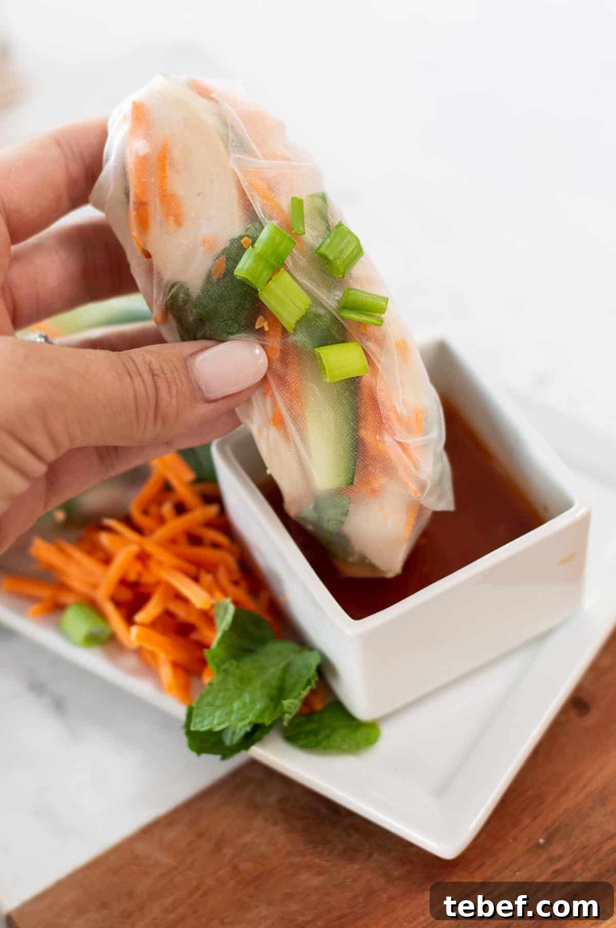 Gluten-Free Spring Rolls Ready in 10 Minutes 2 gluten free spring rolls being dipped in sauce