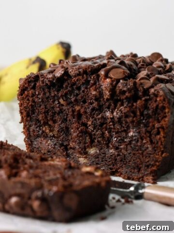 Chocolate banana bread sliced with a knife.