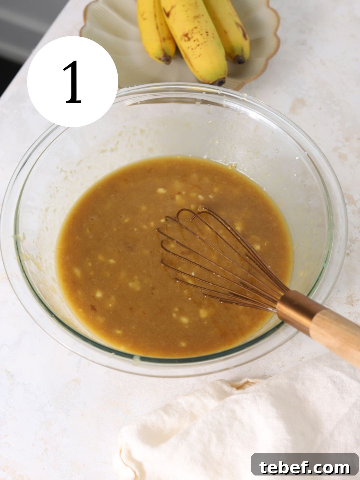 Moist Banana Olive Oil Cake Recipe for Perfect Homemade Dessert 4 A glass mixing bowl with wet ingredients being whisked together.