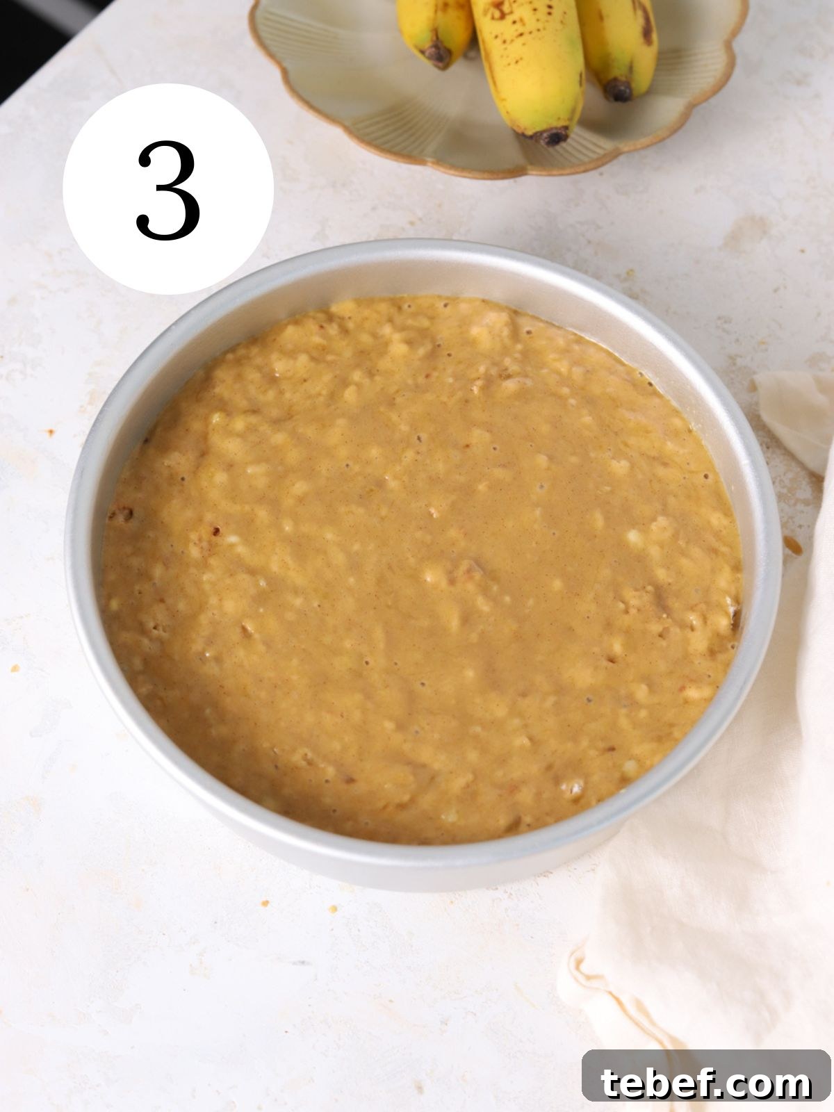 Moist Banana Olive Oil Cake Recipe for Perfect Homemade Dessert 6 A round pan with banana cake batter next to some bananas.