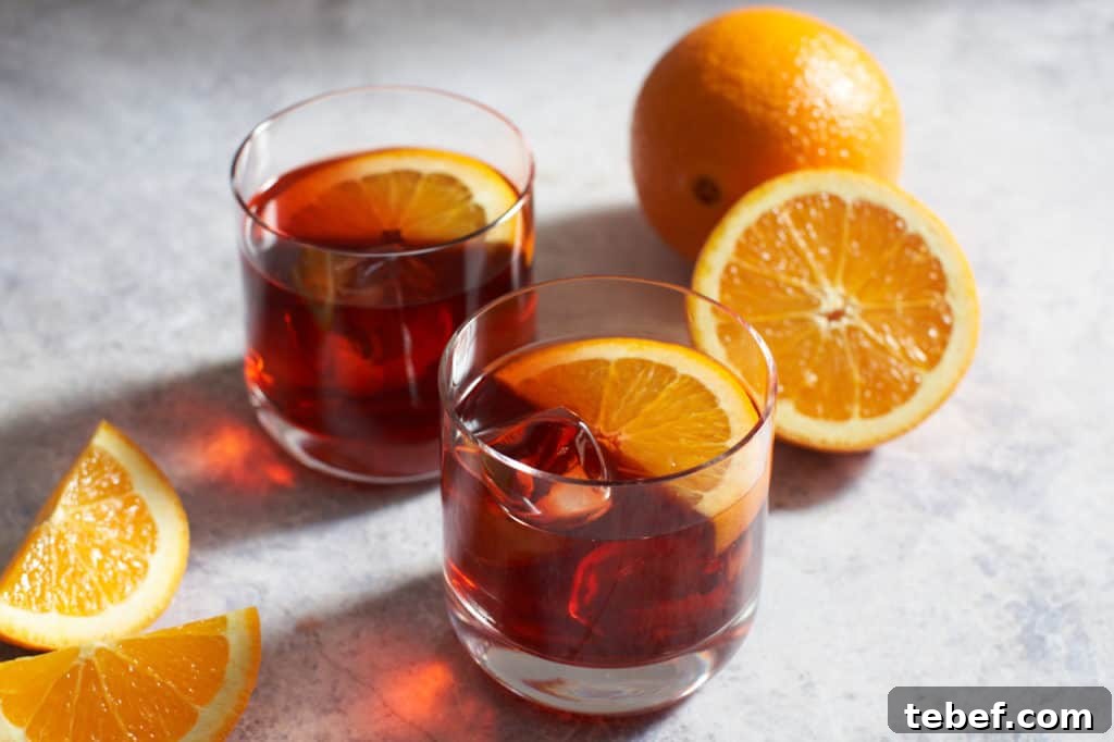 Two mezcal negronis next to sliced oranges.