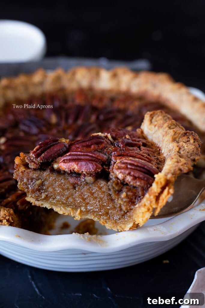 Side view of remove a slice of maple syrup pecan pie fro the pie dish.