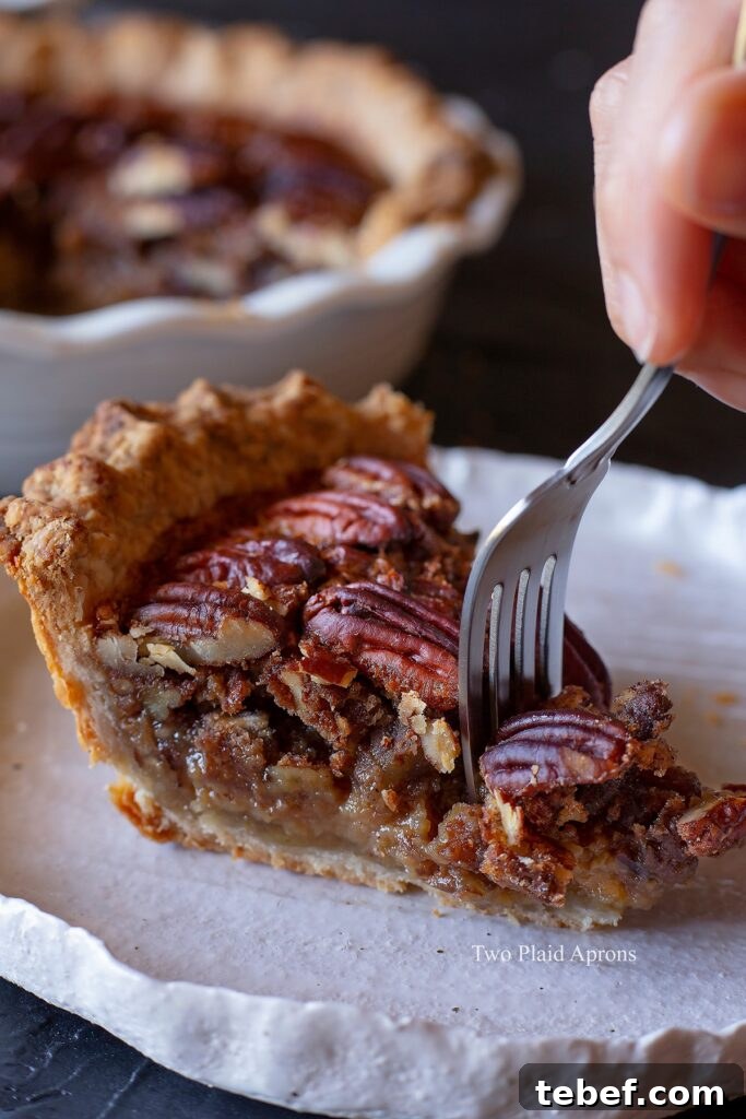 Taking a forkful of maple syrup pecan pie from a slice.