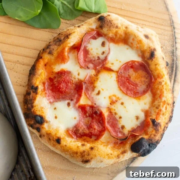 How to Bake Frozen Pizza for Crispy, Restaurant-Style Results 12 Sourdough pizza sitting on a board after being baked with basil and pizza dough in the background.