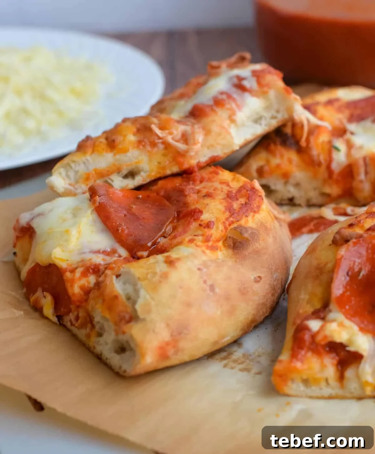 How to Bake Frozen Pizza for Crispy, Restaurant-Style Results 9 Slices of pepperoni pizza are stacked on parchment paper.