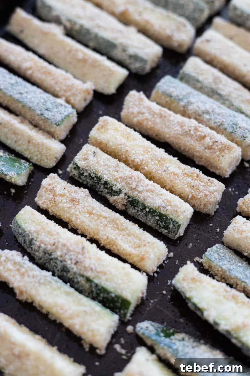 Zucchini slices lined up on a baking sheet. 