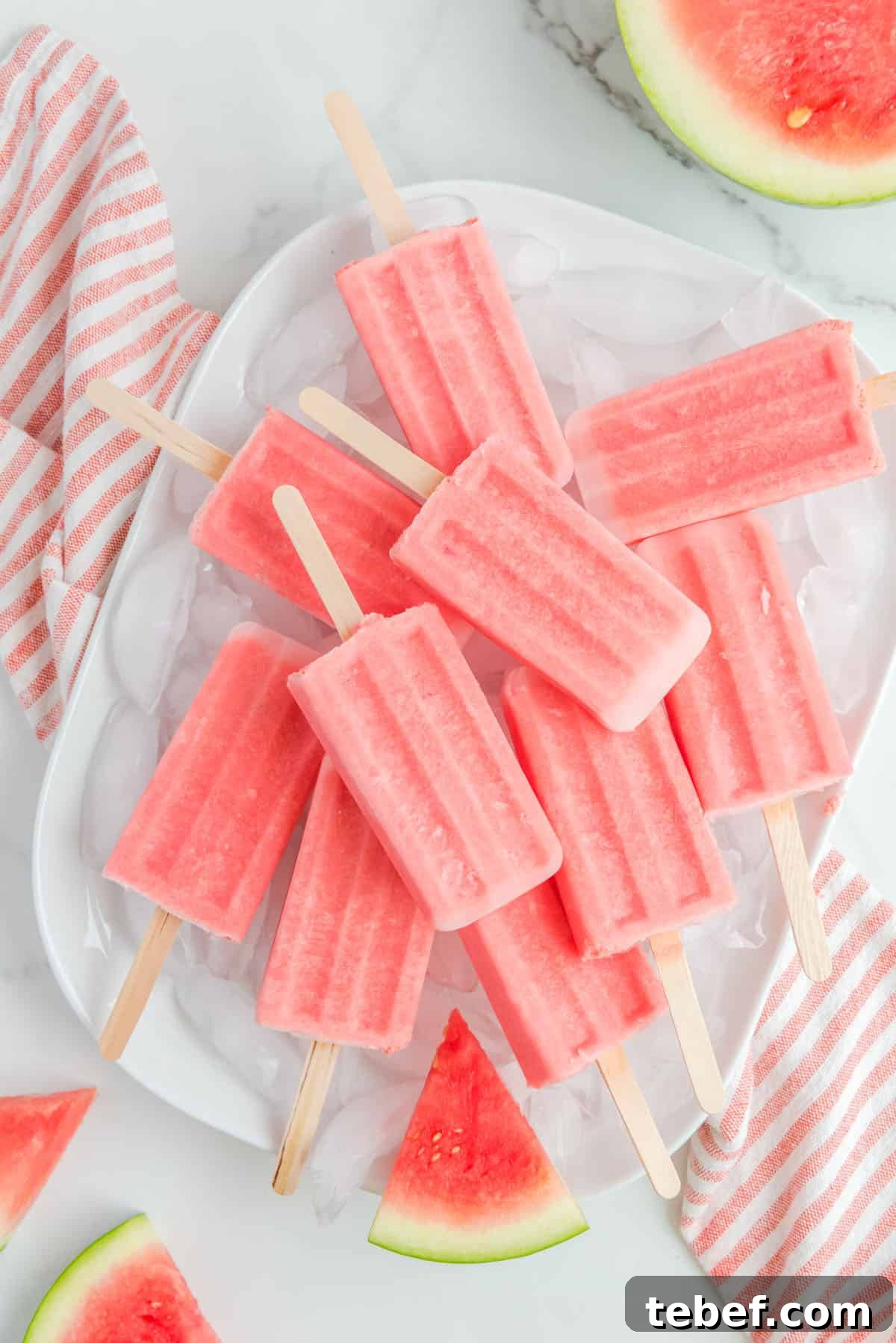 Refreshing Watermelon Popsicle Recipe: 3-Ingredient Frozen Treats 2 A plate of ice cubes topped with the watermelon popsicles stacked on top of each other.