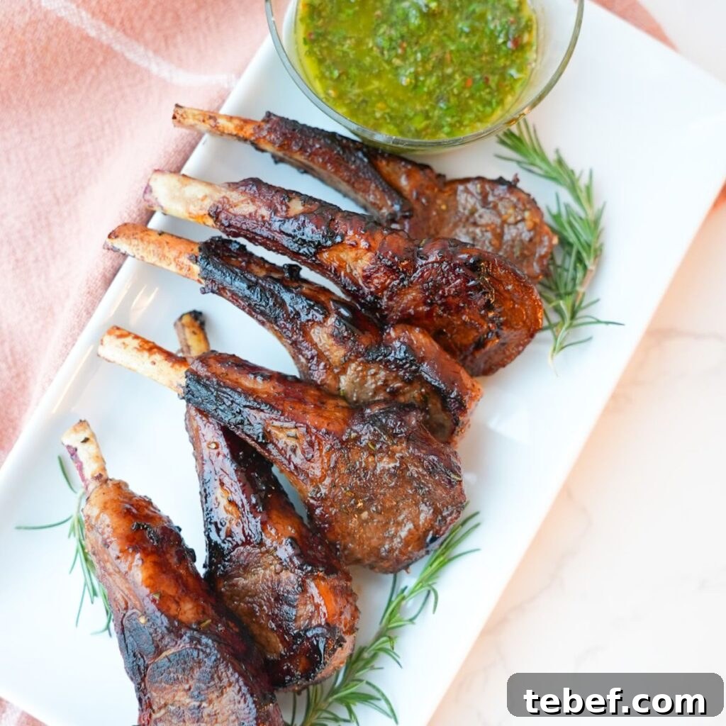 Garlic Herb Lamb Chops with Crispy Seared Edges 2 Lamb chops with a side of mint chimichurri on a plate with visible herbs and a glossy seared crust.