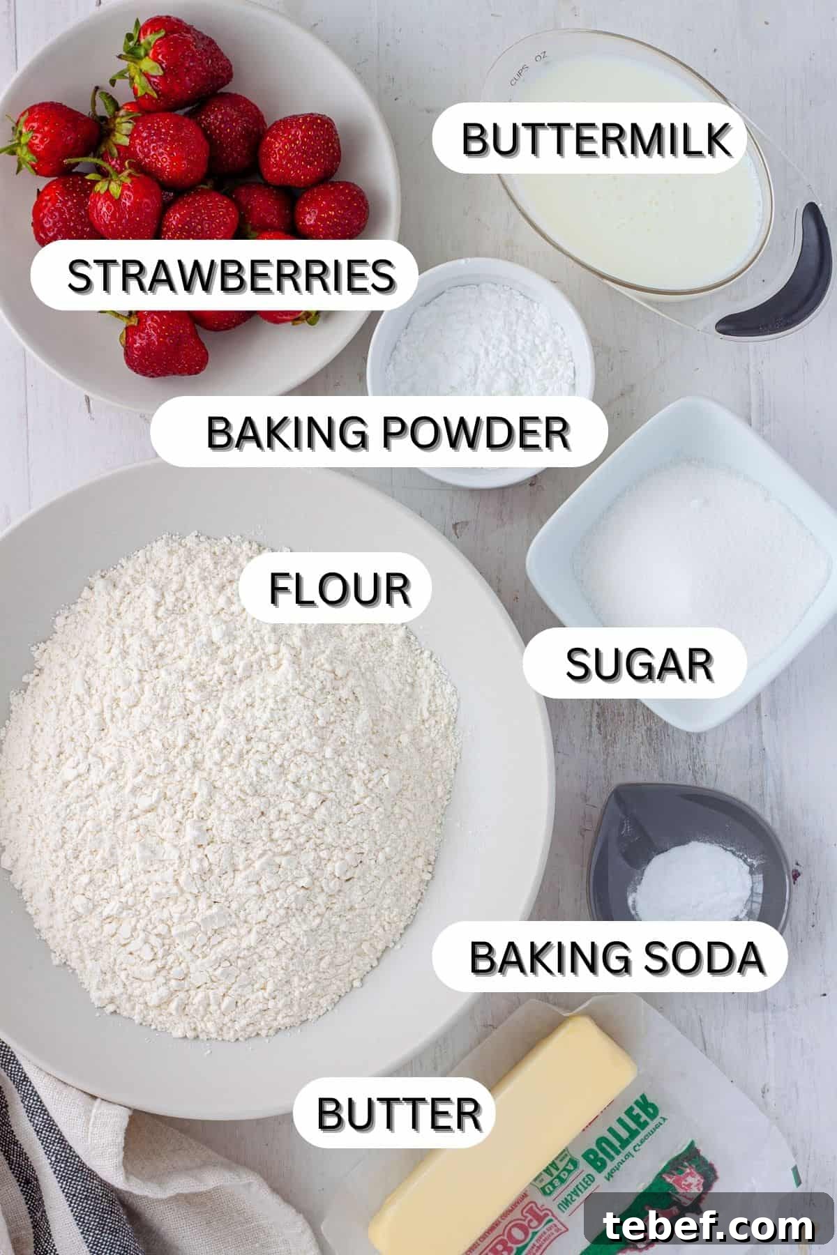 Ingredients for strawberry biscuits on a white table.