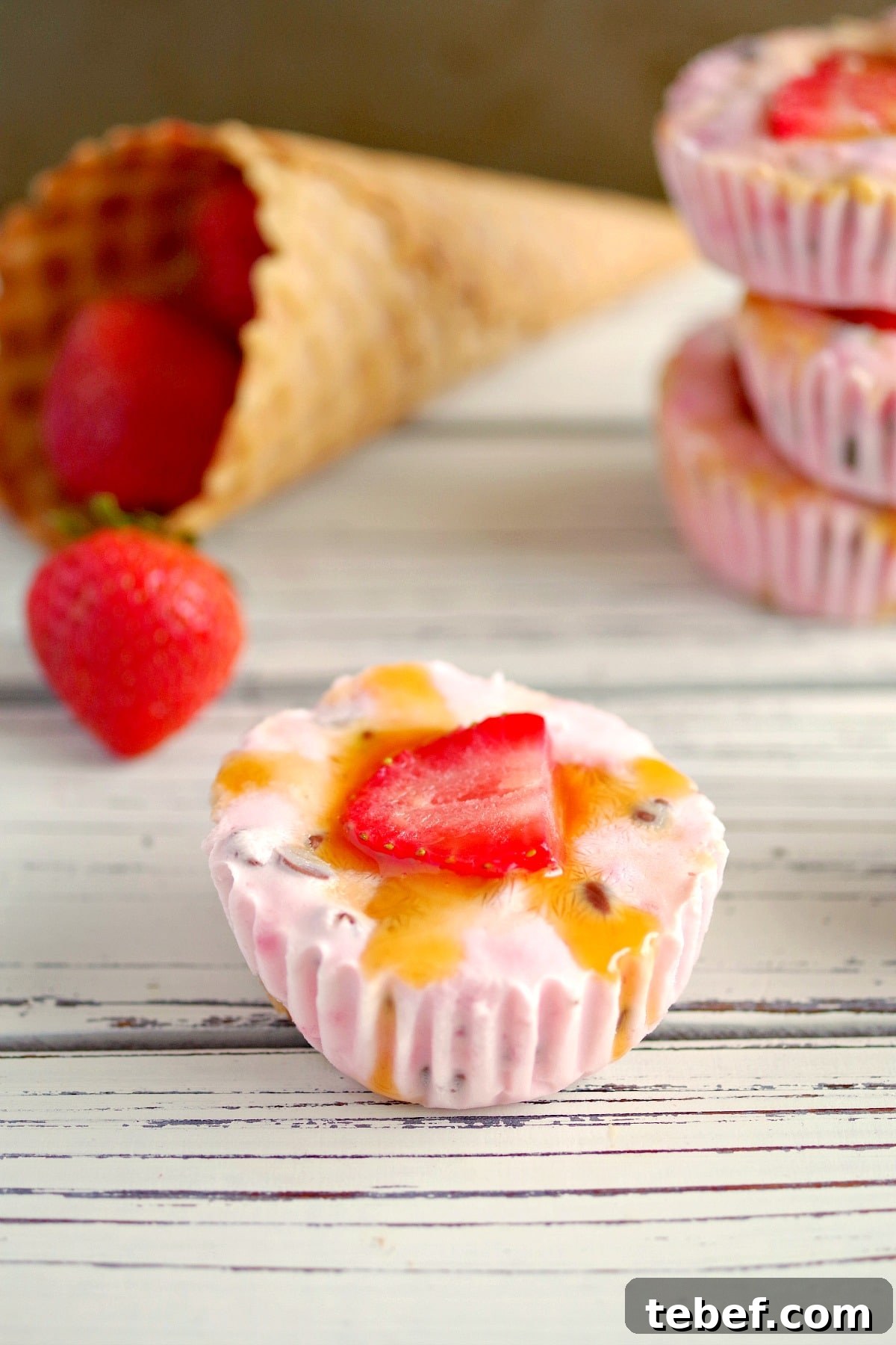 Strawberry Drumstick Frozen Yogurt Cups on white table with strawberries and cones in background