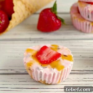 strawberry frozen yogurt cups on a wooden surface with strawberries and cones in the background