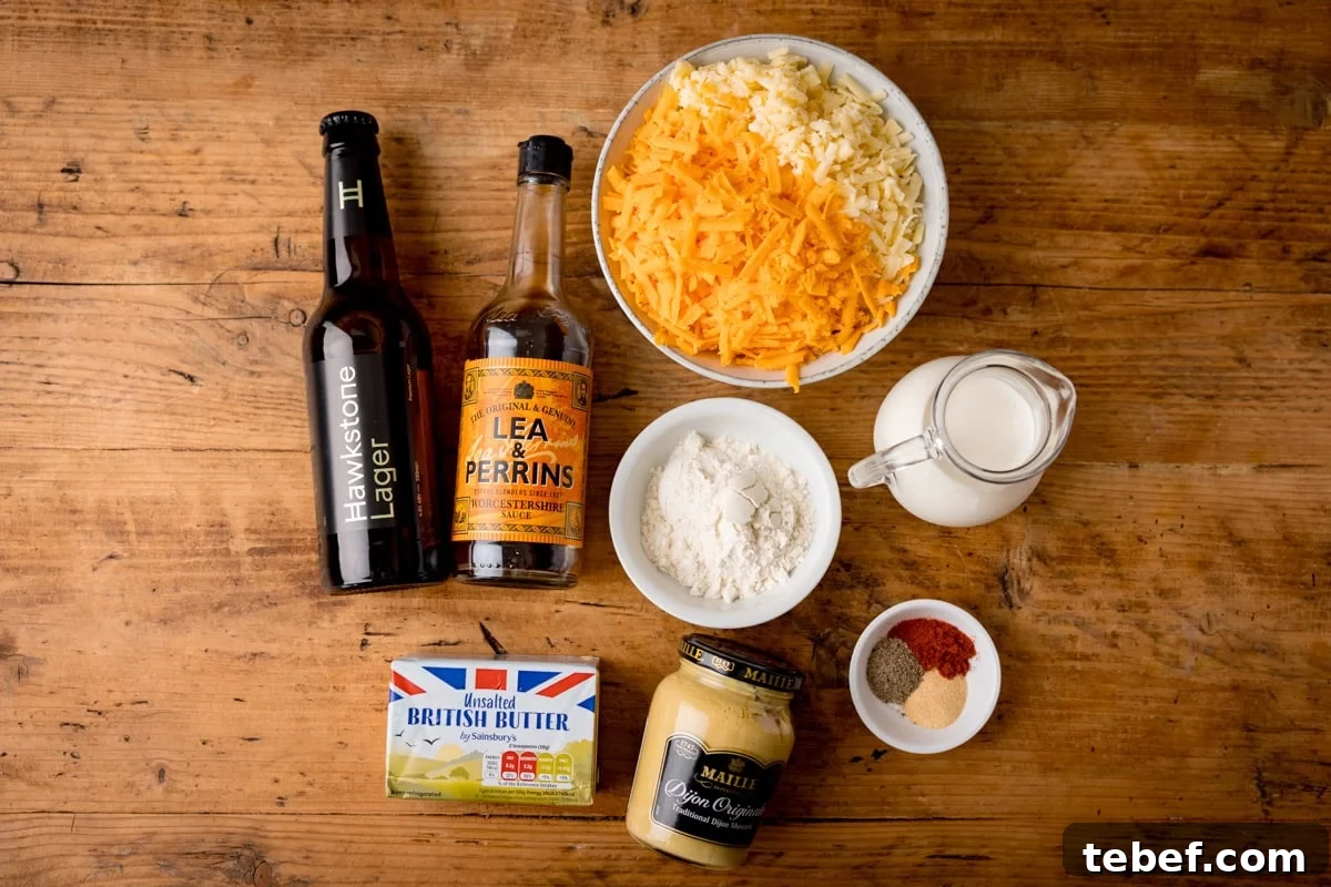 Creamy Beer Cheese Dip Recipe for Game Day and Parties 3 A wooden table displays ingredients for an easy beer cheese dip: a bowl of grated cheese, a bottle of lager, Worcestershire sauce, butter, flour, milk, mustard, and spices—all ready to make a warm beer cheese dip.